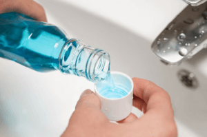 Mouthwash being poured into the cap over sink